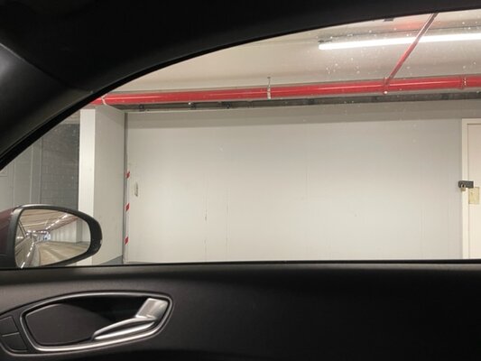 Achter deze houten wand  bevind zich een groot parkeergarage